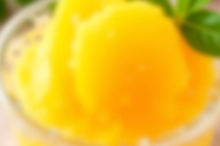 Bright orange mango sorbetto in a chilled glass bowl with fresh mango slices.